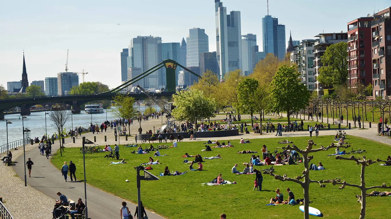 Viele Menschen am Frankfurter Mainufer, im Hintegrund die Skyline der Stadt